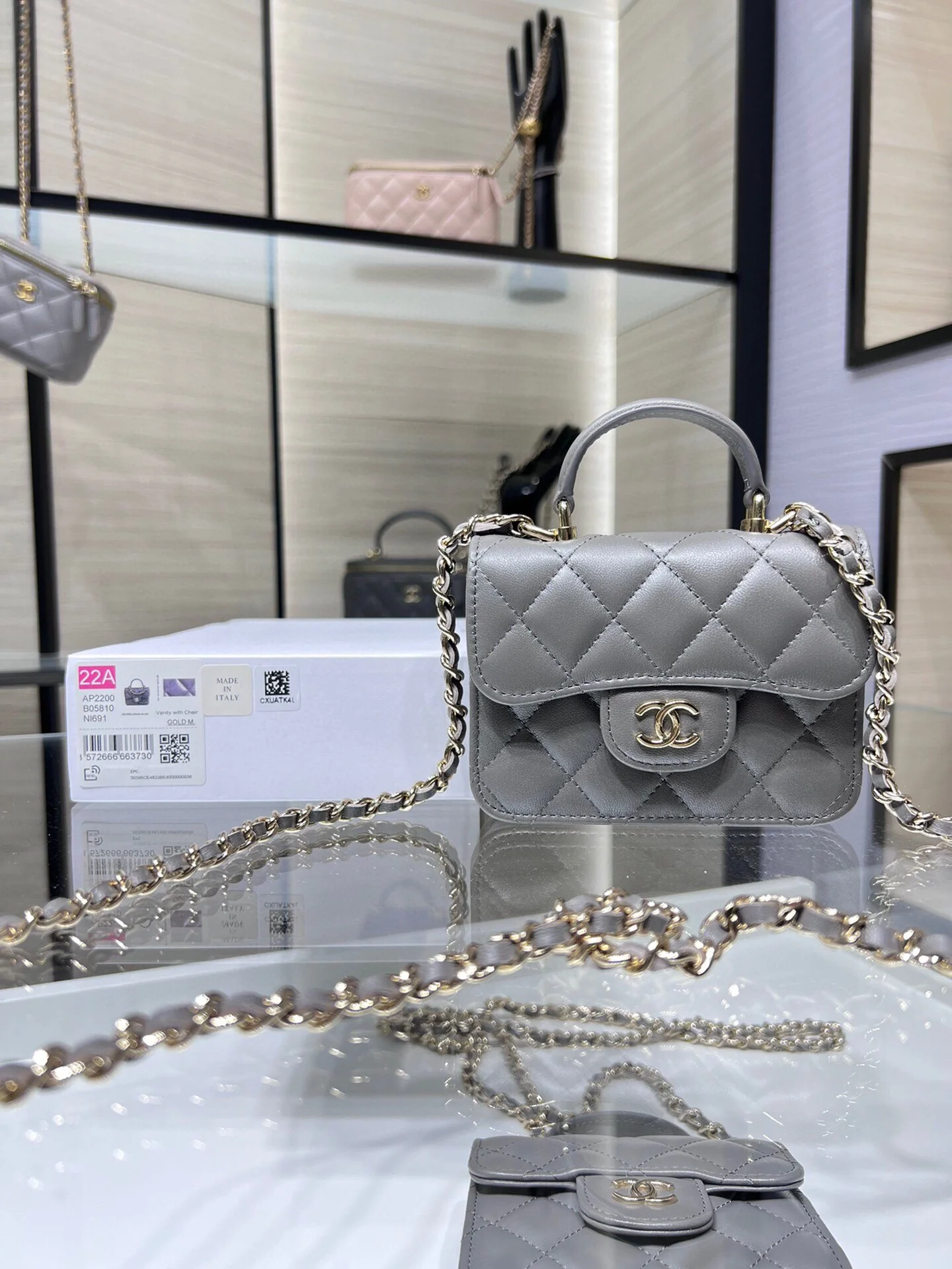 Сумка Chanel из коллекции Métiers d'Art 2022 года — маленькая сумка с цепочкой и ручкой — серая.