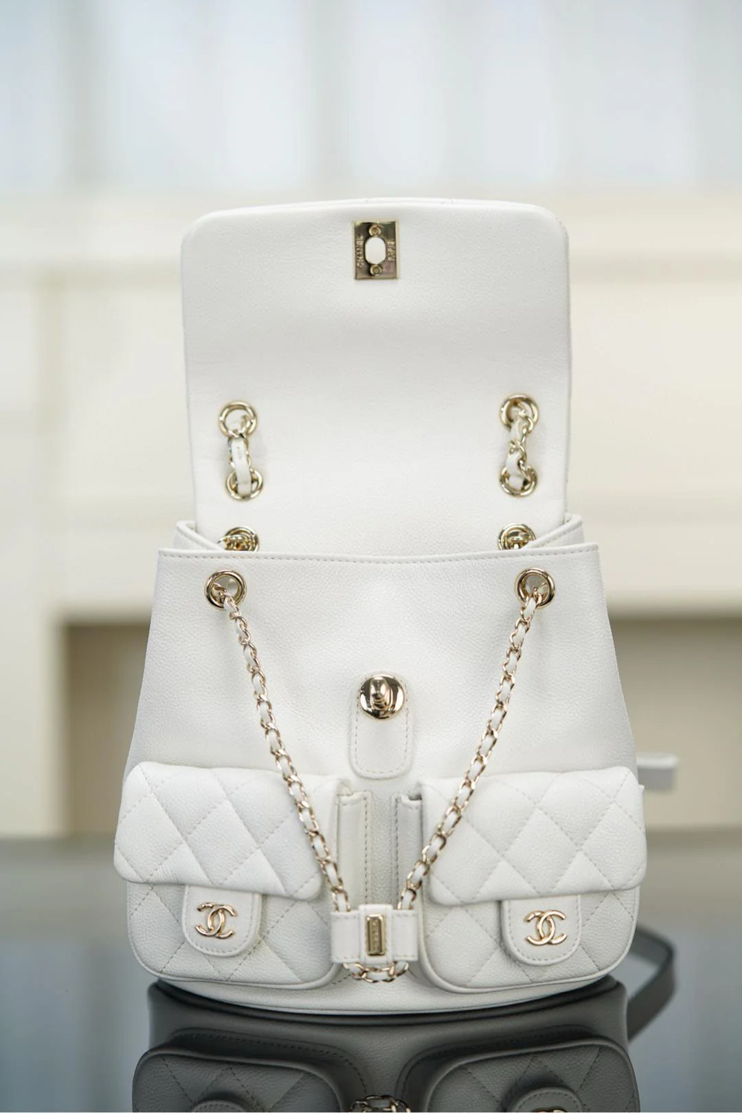 Рюкзак Chanel Duma 24a, белый с золотой пряжкой.