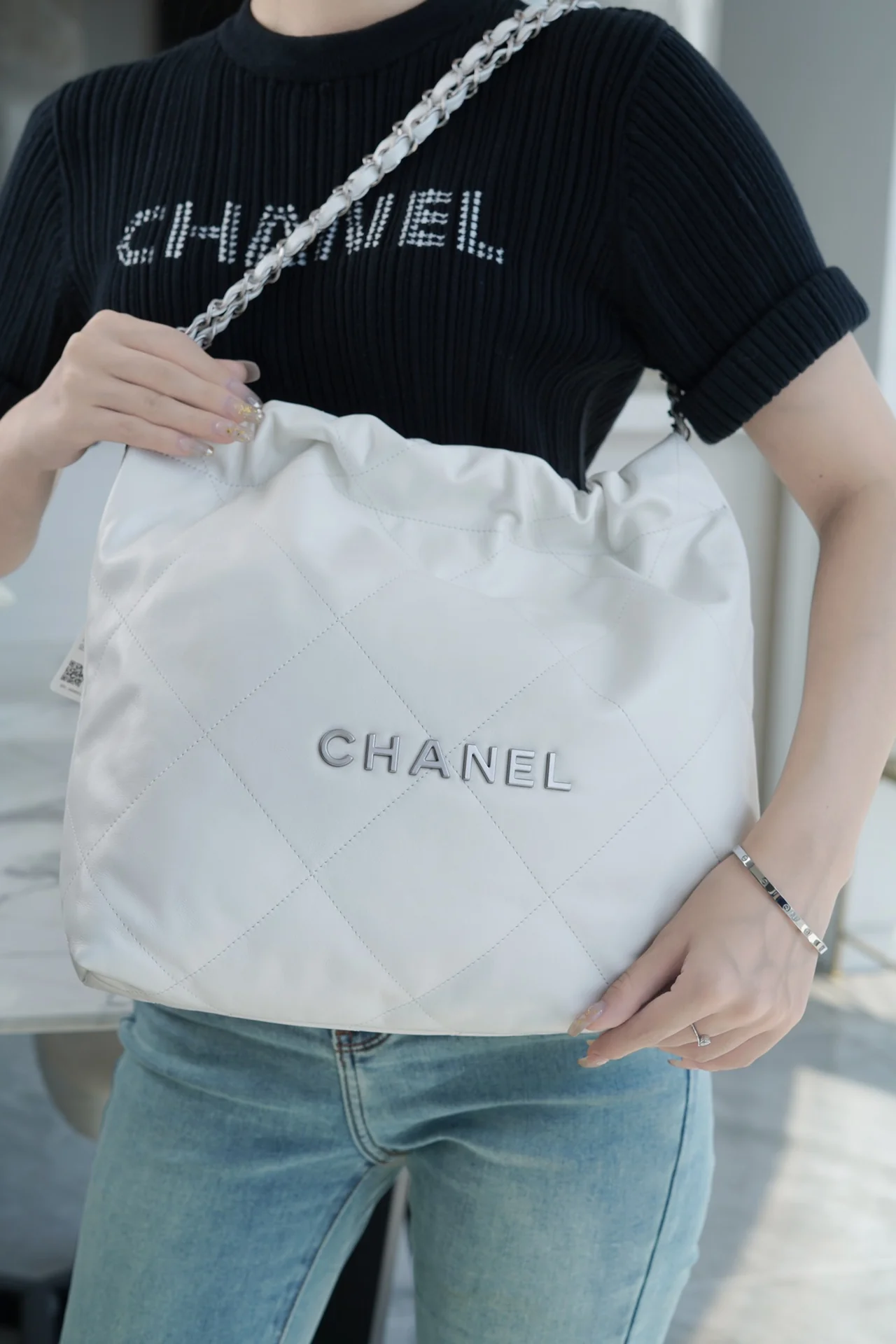 Сумочка Chanel No. 22 — маленькая, белая, серебристая.