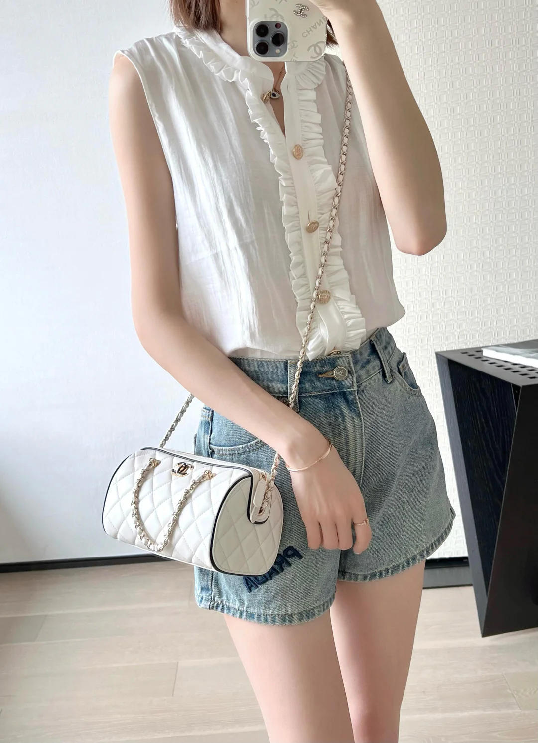 Мини-сумка-котелок Chanel 25p из овечьей кожи, белая с черной отделкой и светло-золотистой пряжкой.