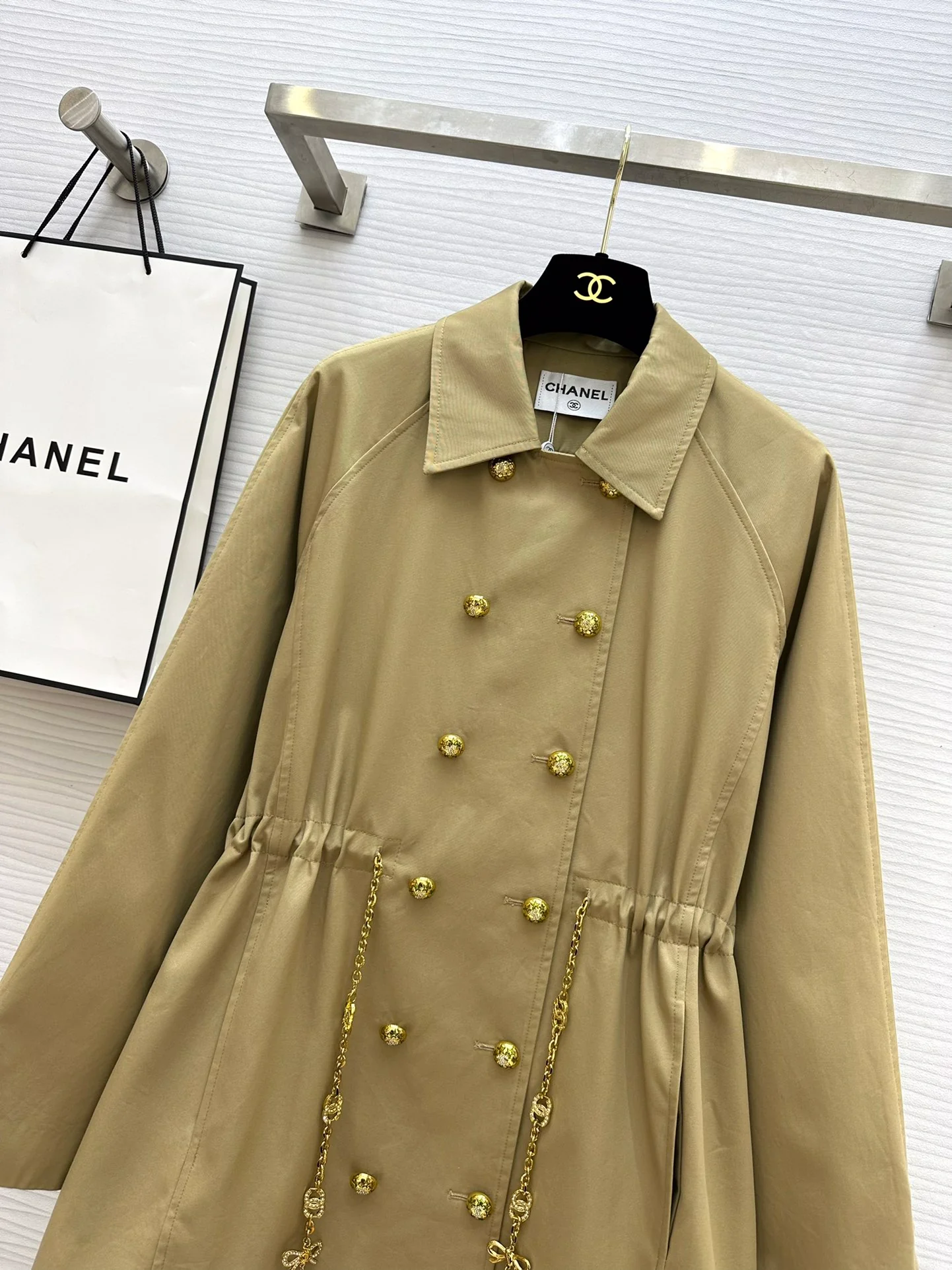 Новая коллекция Chanel весна/лето 2024: двубортный тренч, украшенный цепочками.