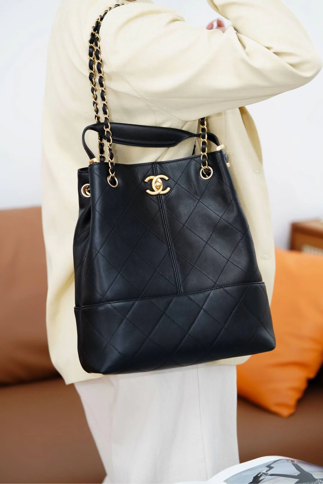 Сумка-ведро Chanel Métiers d'Art — черная с золотой фурнитурой.