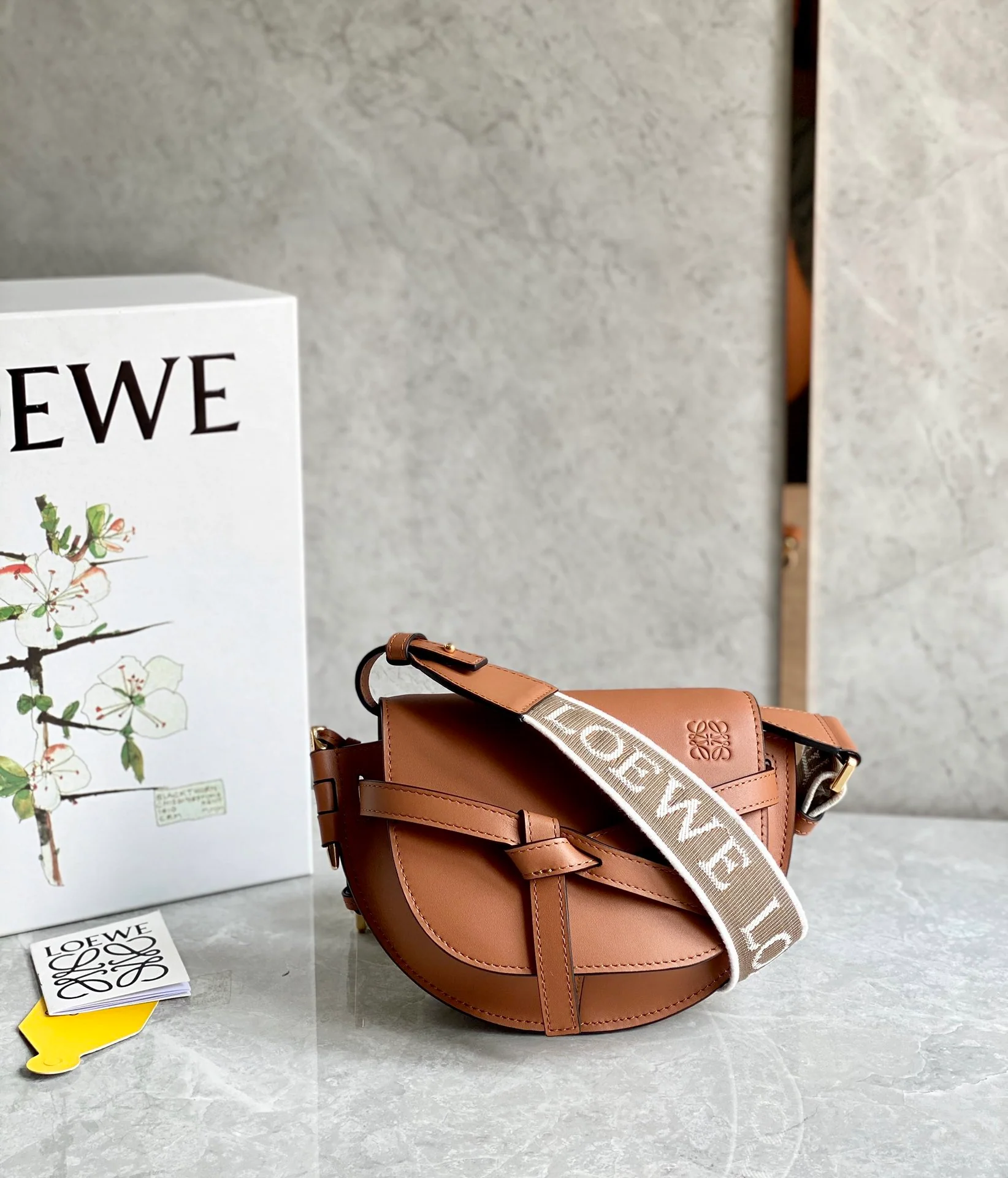 Сумка Loewe Gate Mini 21x12x5x9x5 см с широким плечевым ремнем и надписью.