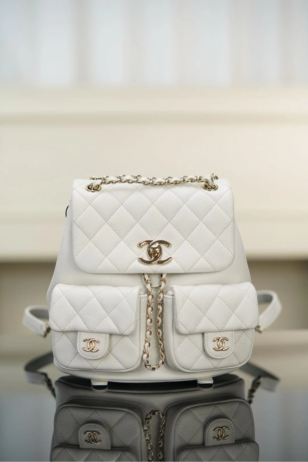 Рюкзак Chanel Duma 24a, белый с золотой пряжкой.