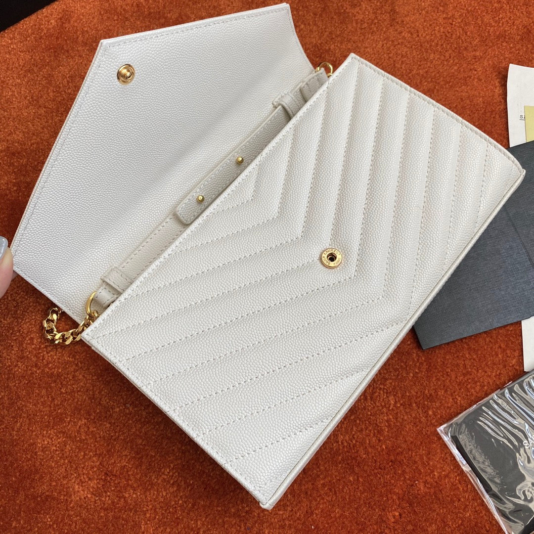 Сумочка-конверт YSL с монограммой из икры — белая с золотой фурнитурой.