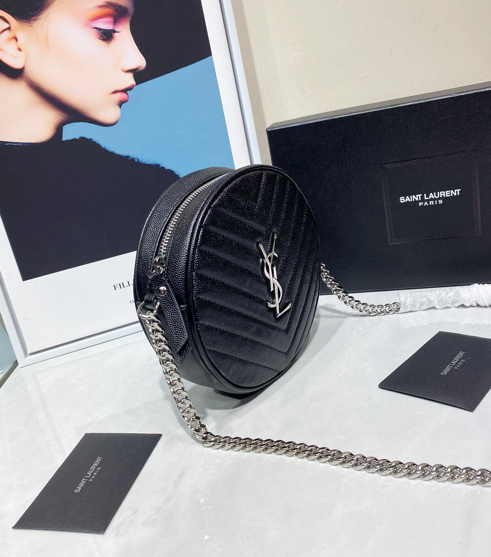 Маленькая круглая сумка YSL Vinyle - черная с серебристой фурнитурой.