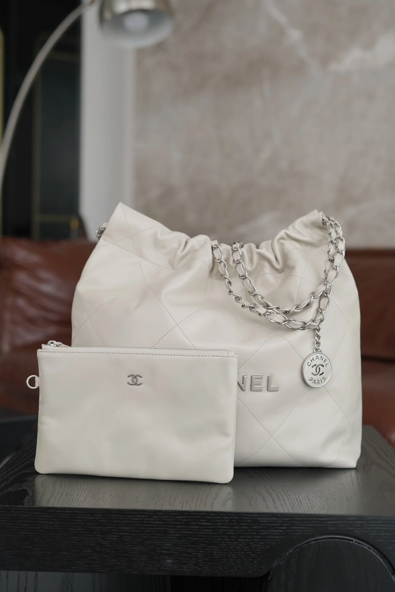 Маленькая белая сумочка Chanel с серебряной пряжкой на задней части.