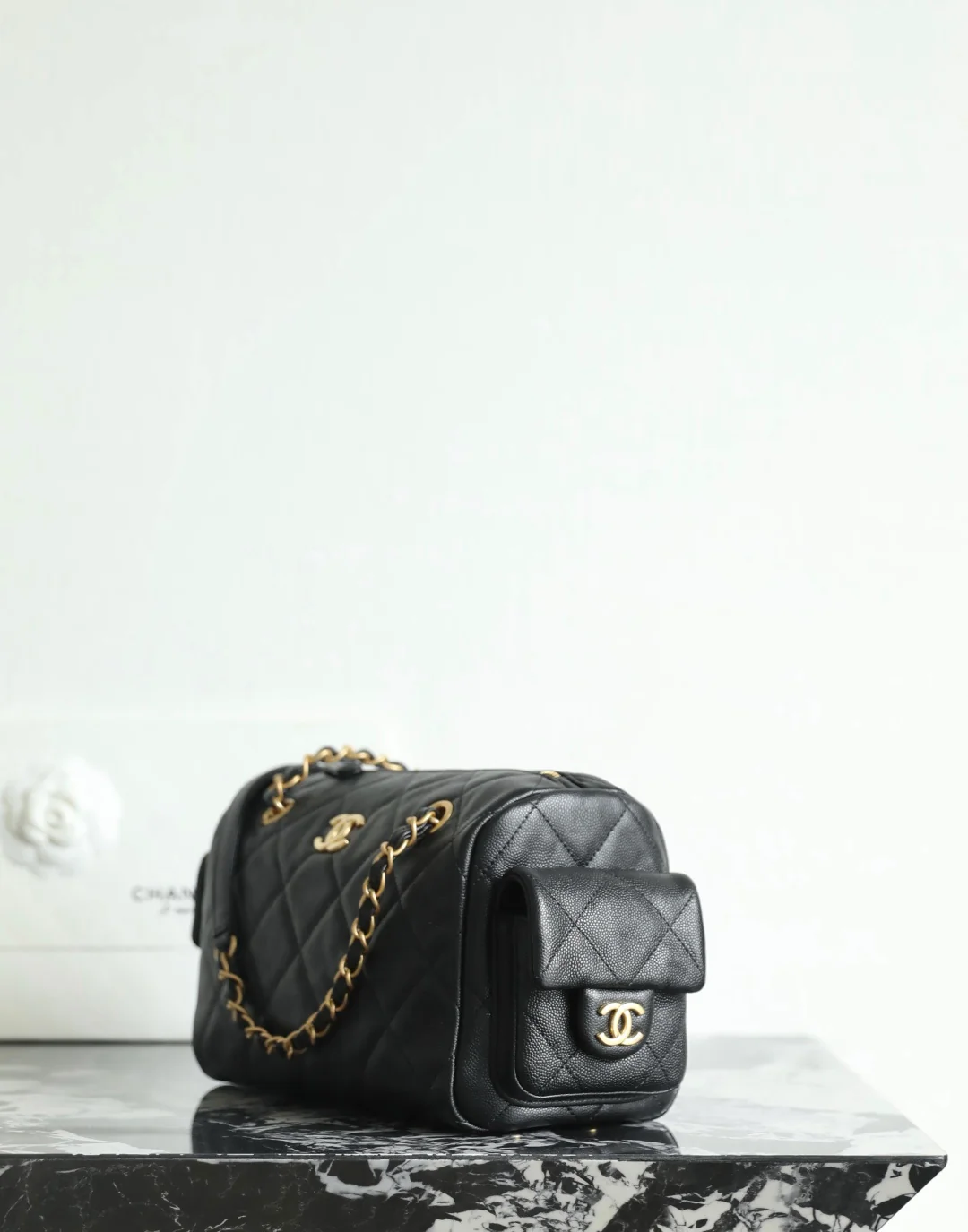 Сумка-боулинг Chanel 25k с двумя карманами — черная кожа с золотой пряжкой и маленьким шариком.