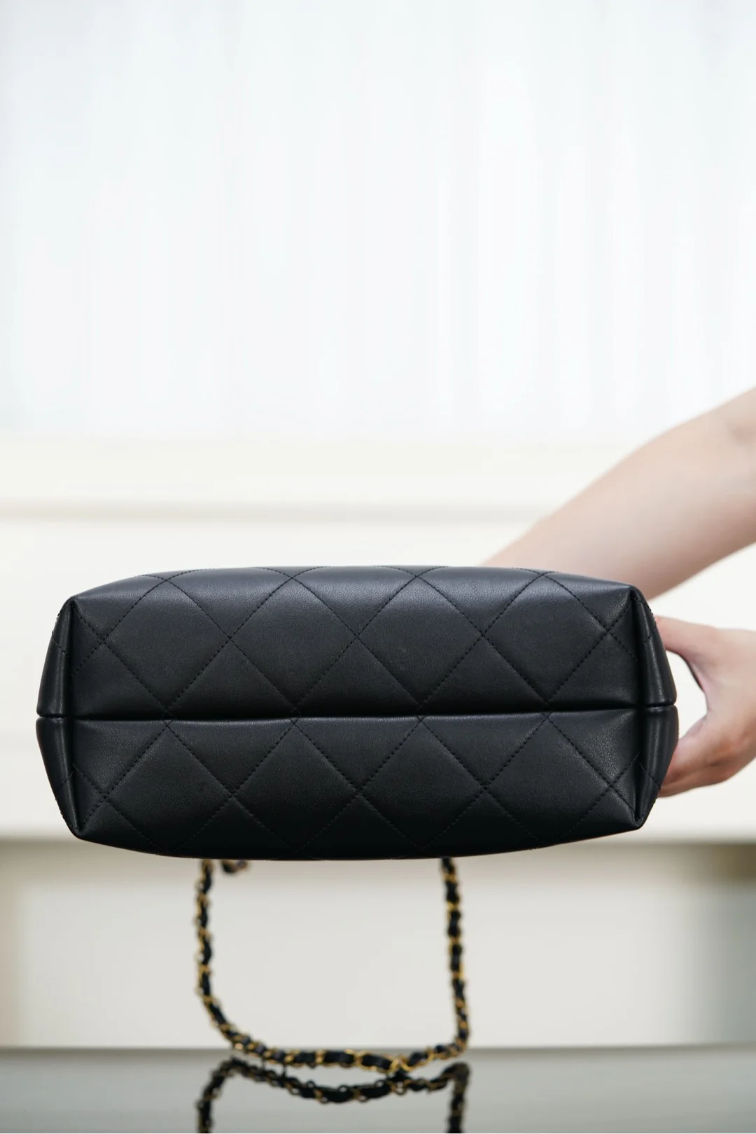 Сумка-ведро Chanel Métiers d'Art — черная с золотой фурнитурой.