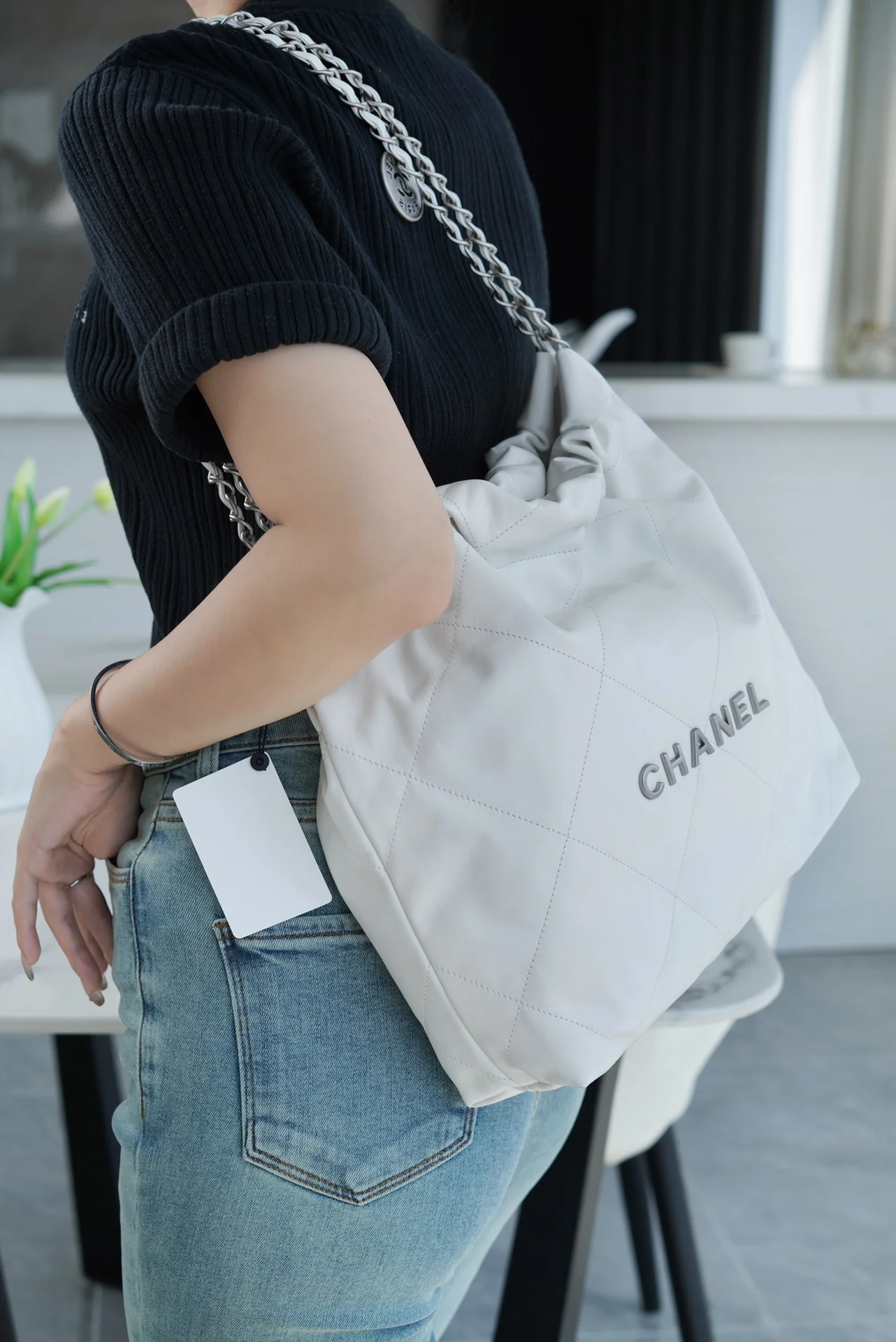 Сумочка Chanel No. 22 — маленькая, белая, серебристая.