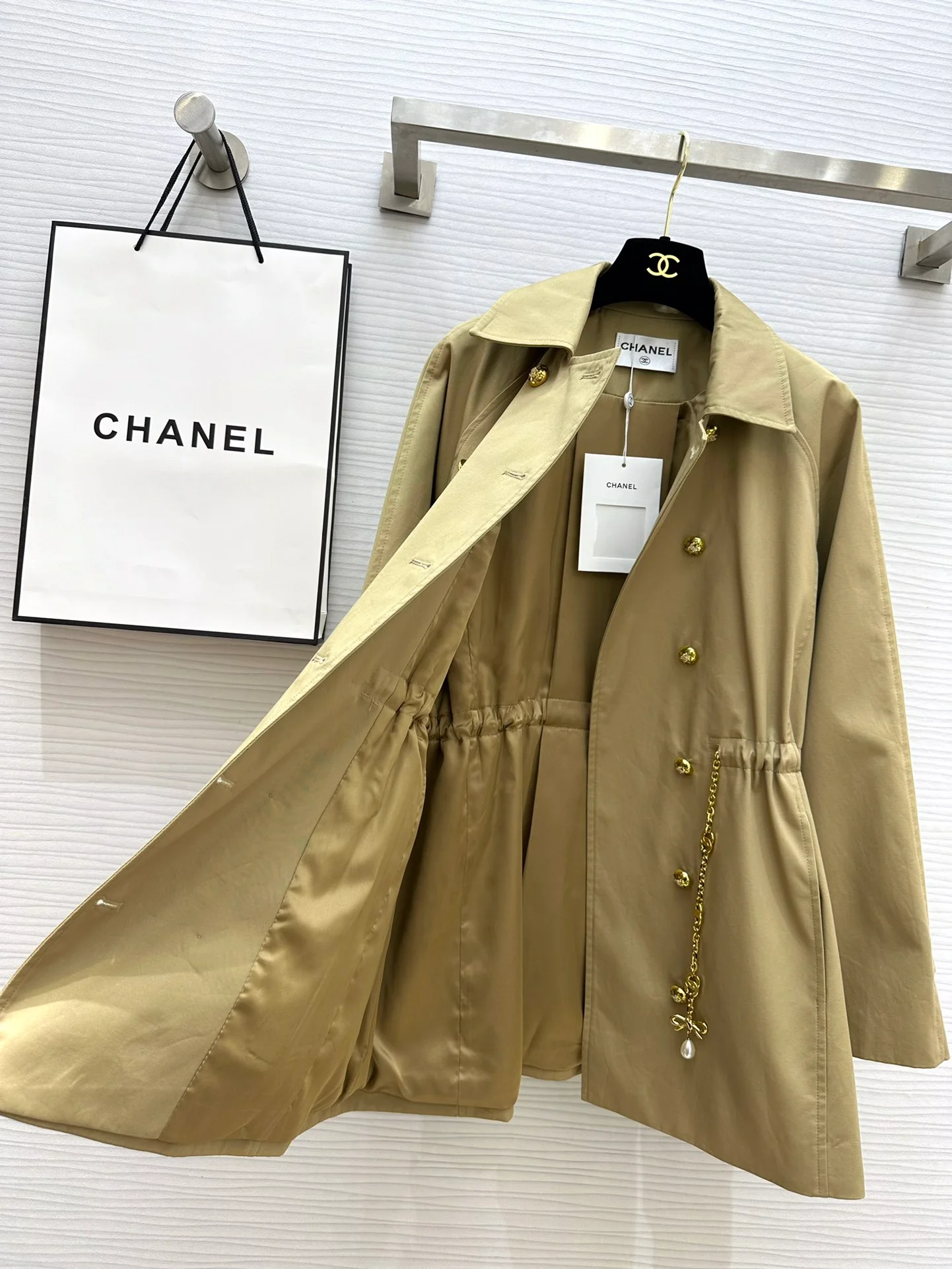 Новая коллекция Chanel весна/лето 2024: двубортный тренч, украшенный цепочками.