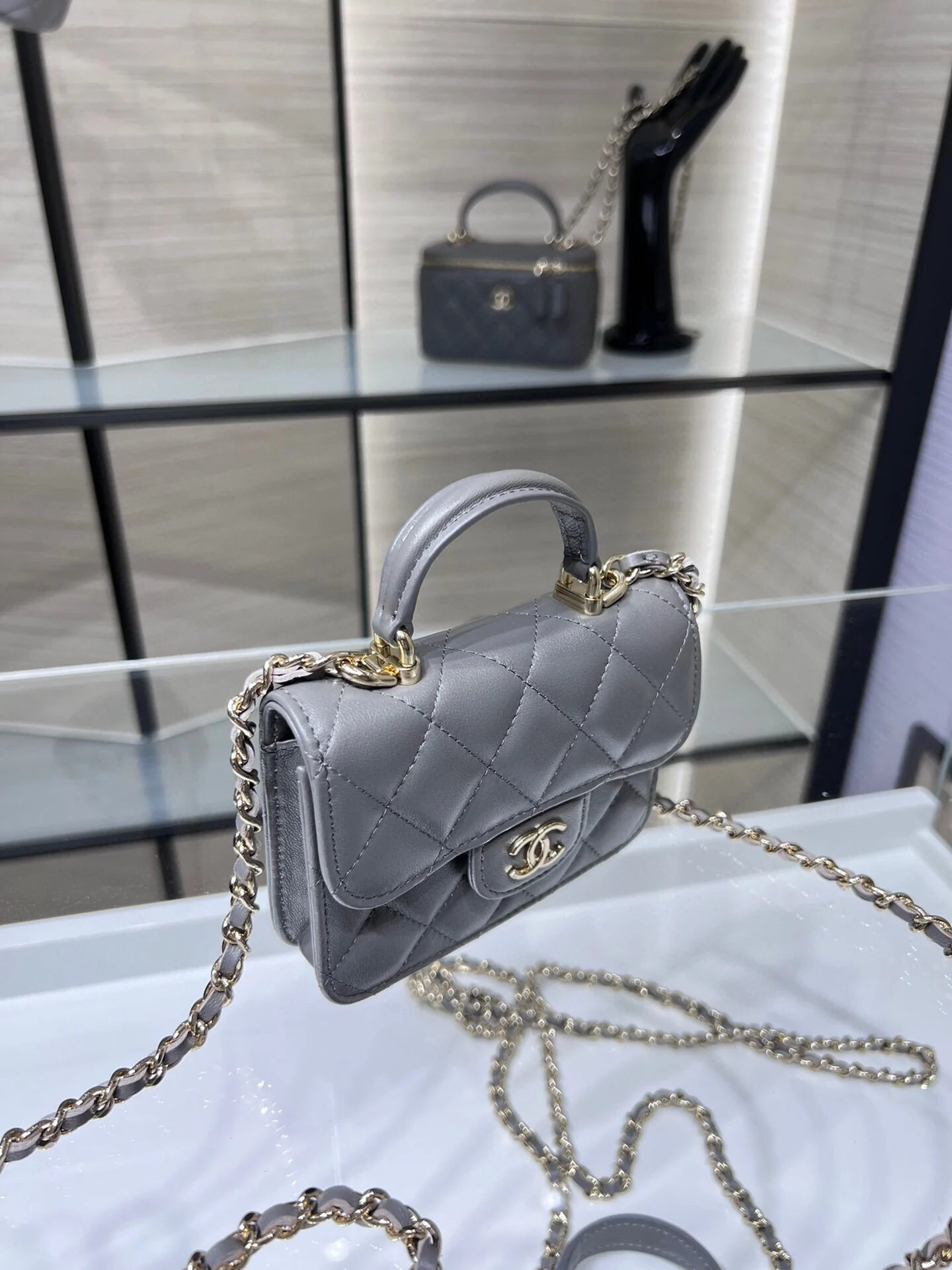 Сумка Chanel из коллекции Métiers d'Art 2022 года — маленькая сумка с цепочкой и ручкой — серая.