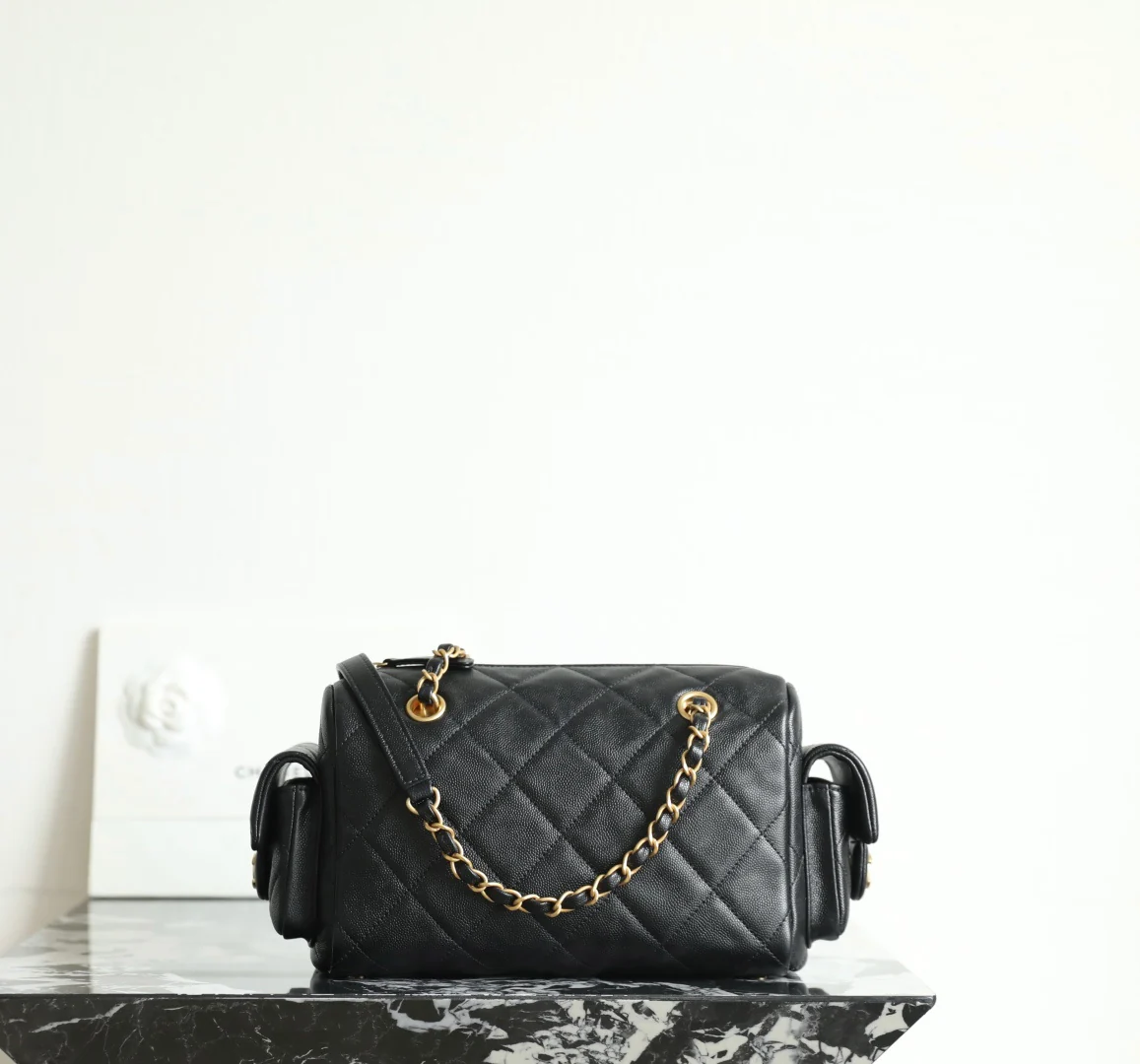 Сумка-боулинг Chanel 25k с двумя карманами — черная кожа с золотой пряжкой и маленьким шариком.