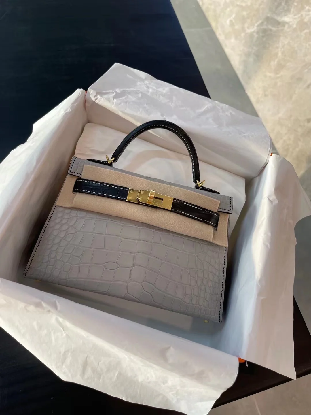 Миниатюрная сумка Hermes Kelly Mini 2-го поколения из матовой кожи аллигатора — жемчужно-серая и черная с золотой фурнитурой.