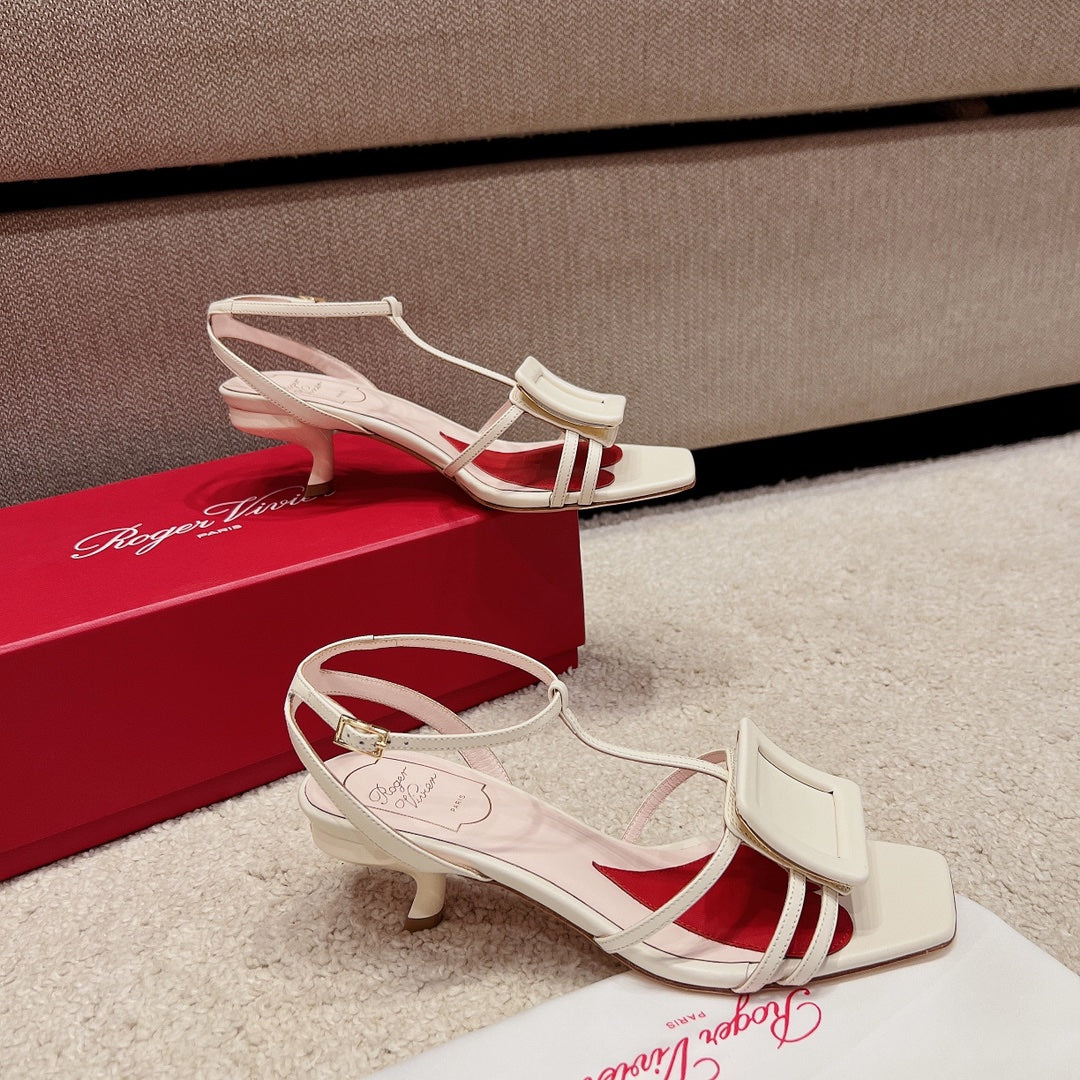 Сандалии RV Shoes - белые, с квадратной пряжкой, на низком каблуке и ремешками.