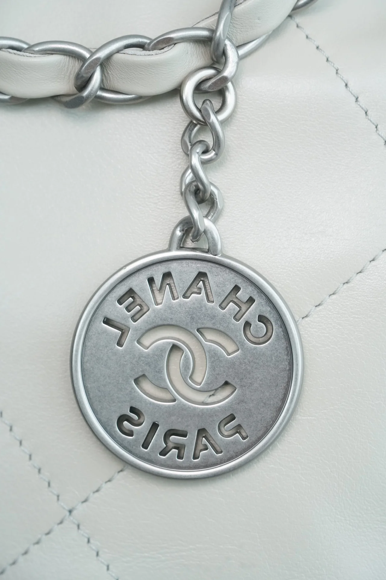 Маленькая белая сумочка Chanel с серебряной пряжкой на задней части.