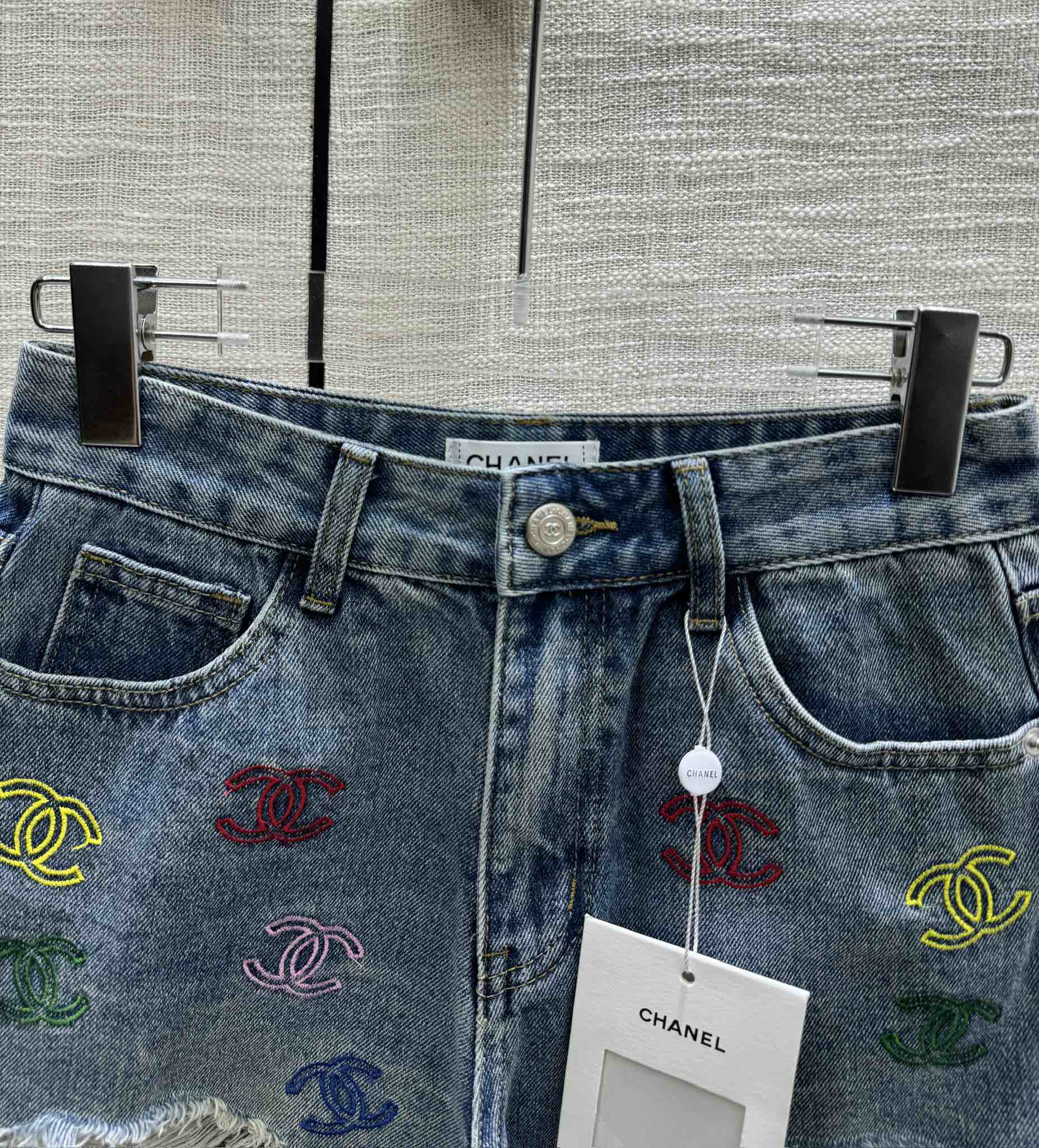 Джинсовые шорты прямого кроя Chanel 2403 с вышитым логотипом и рваными штанинами.
