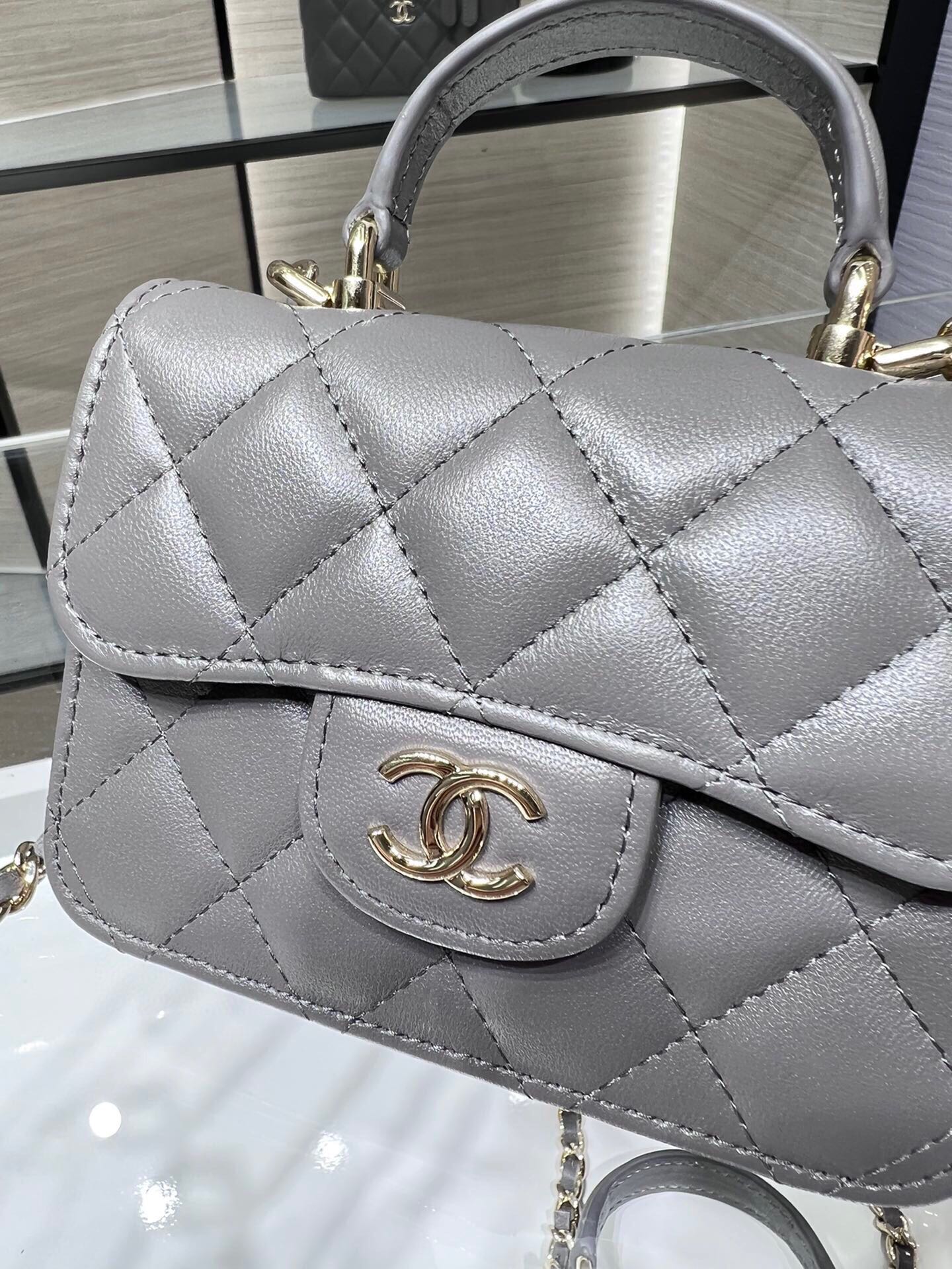 Сумка Chanel из коллекции Métiers d'Art 2022 года — маленькая сумка с цепочкой и ручкой — серая.