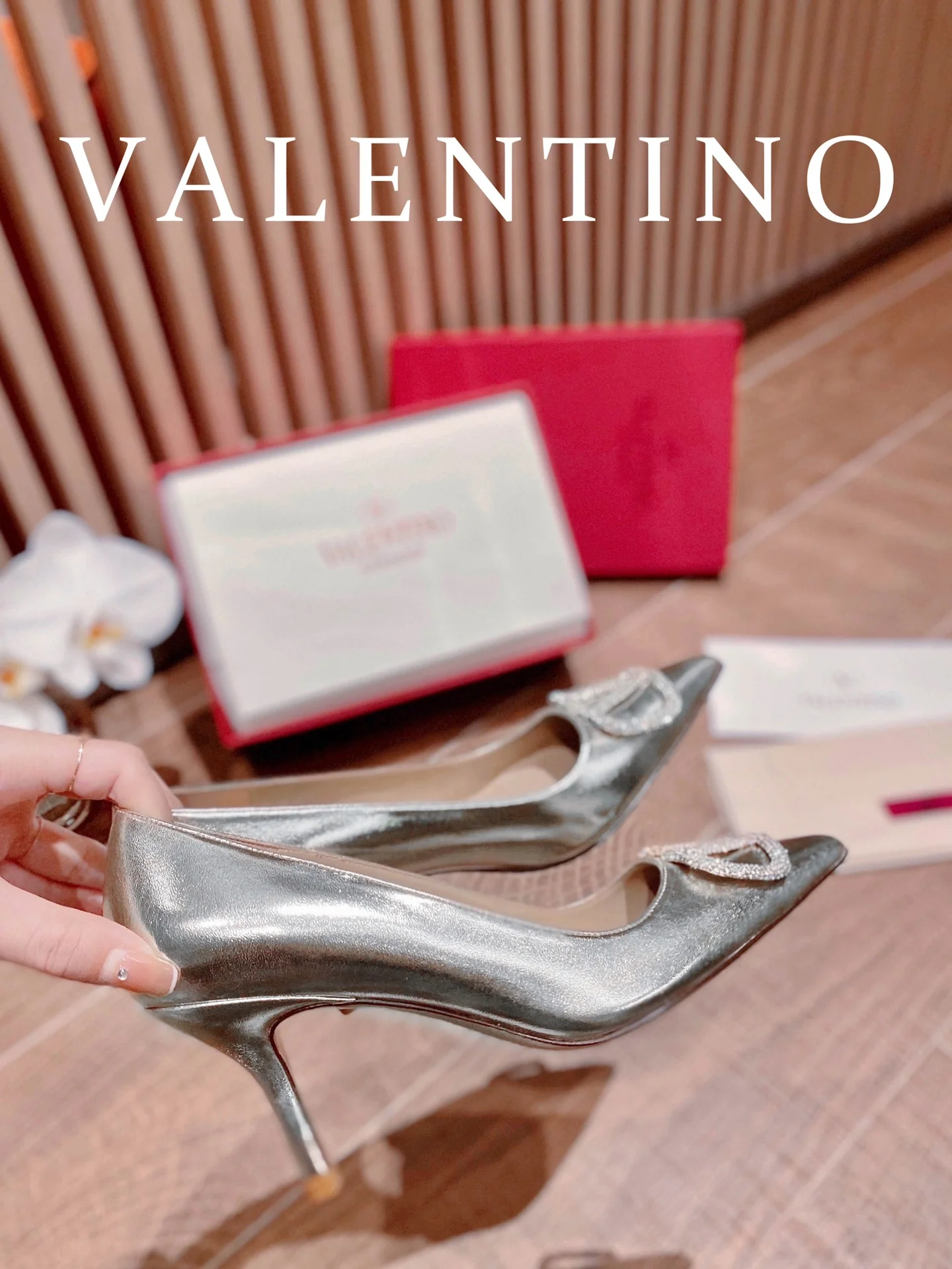 Туфли Valentino на каблуке с V-образным вырезом и бриллиантовой пряжкой — серебристые.