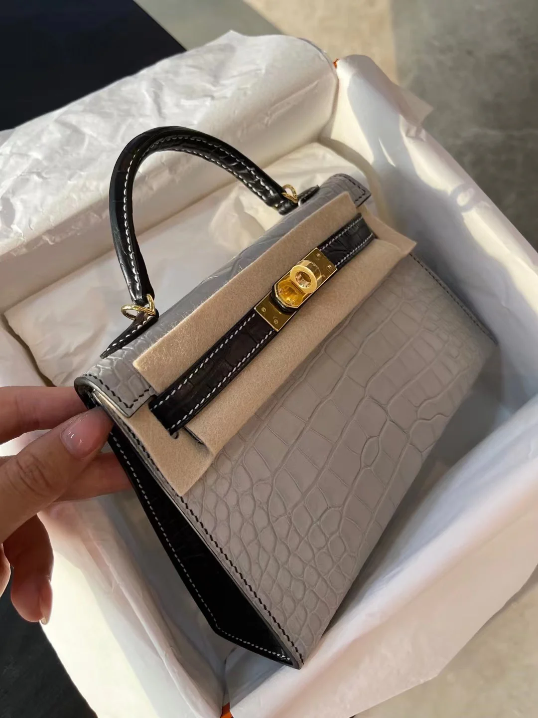 Миниатюрная сумка Hermes Kelly Mini 2-го поколения из матовой кожи аллигатора — жемчужно-серая и черная с золотой фурнитурой.