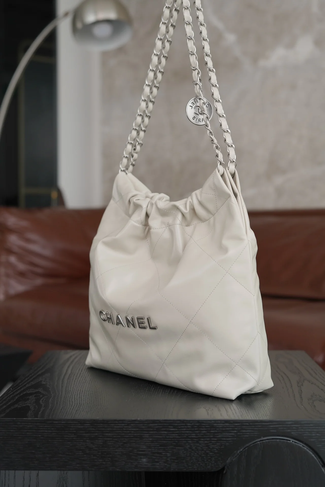 Маленькая белая сумочка Chanel с серебряной пряжкой на задней части.