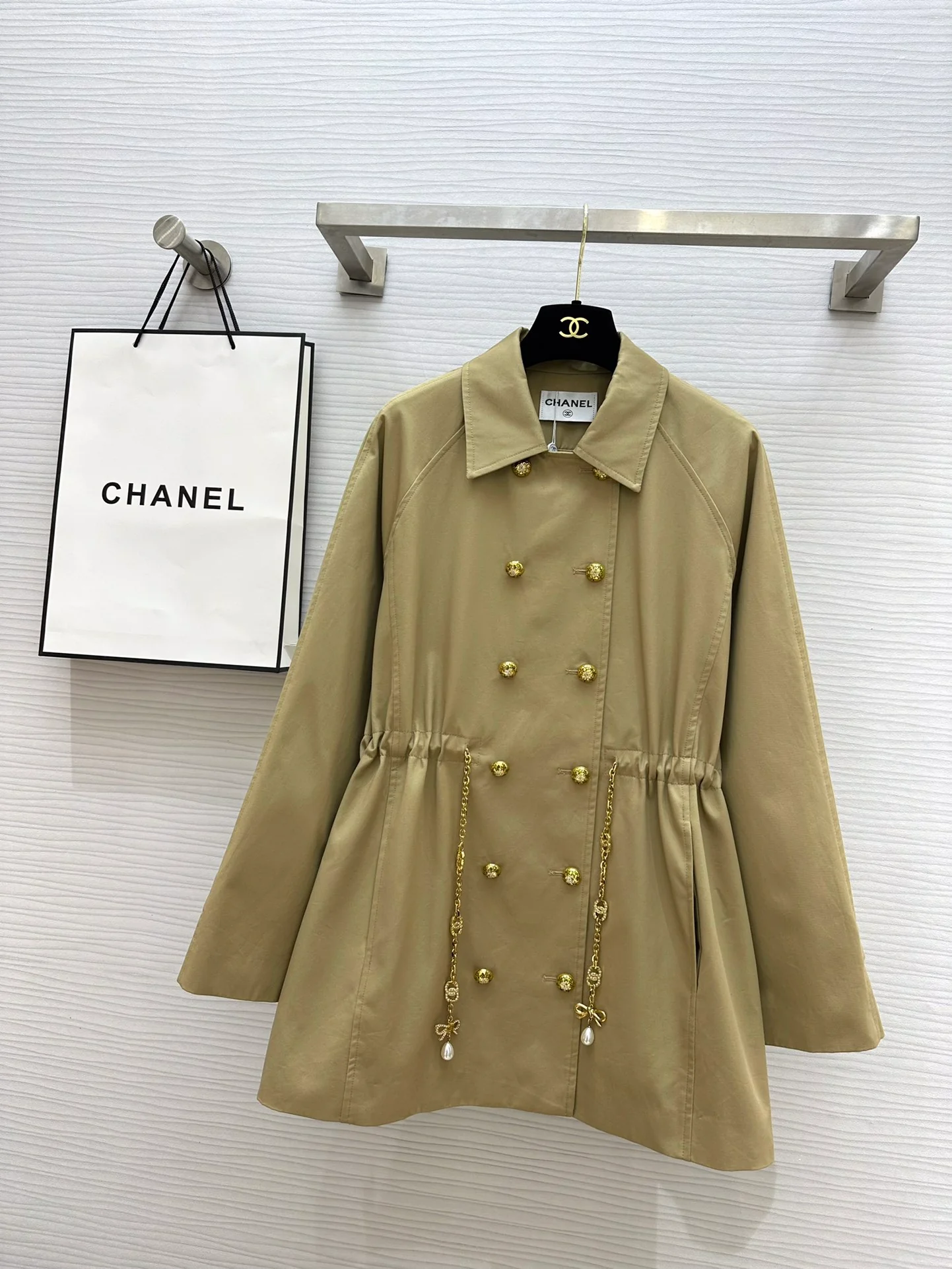 Новая коллекция Chanel весна/лето 2024: двубортный тренч, украшенный цепочками.