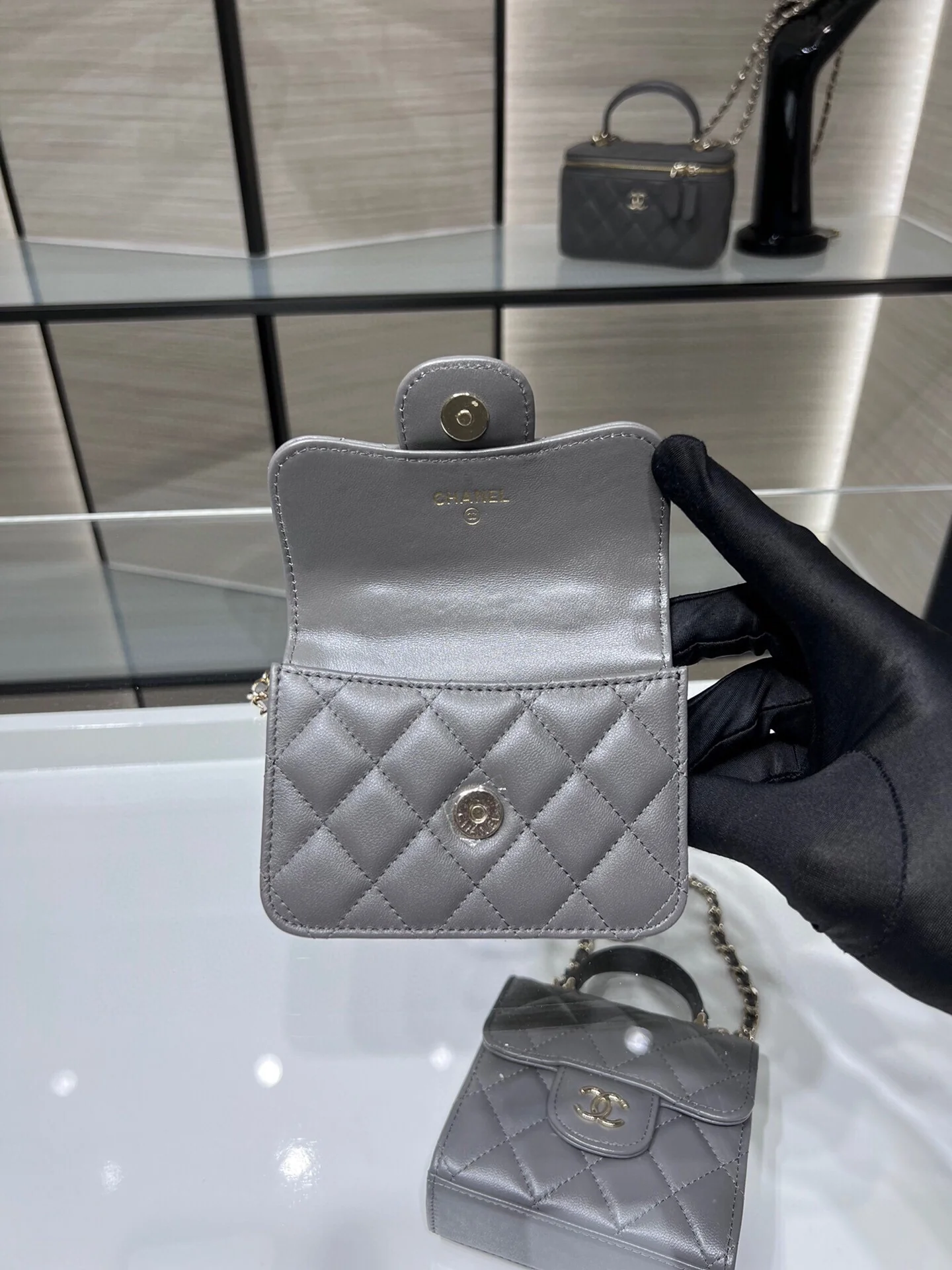 Сумка Chanel из коллекции Métiers d'Art 2022 года — маленькая сумка с цепочкой и ручкой — серая.