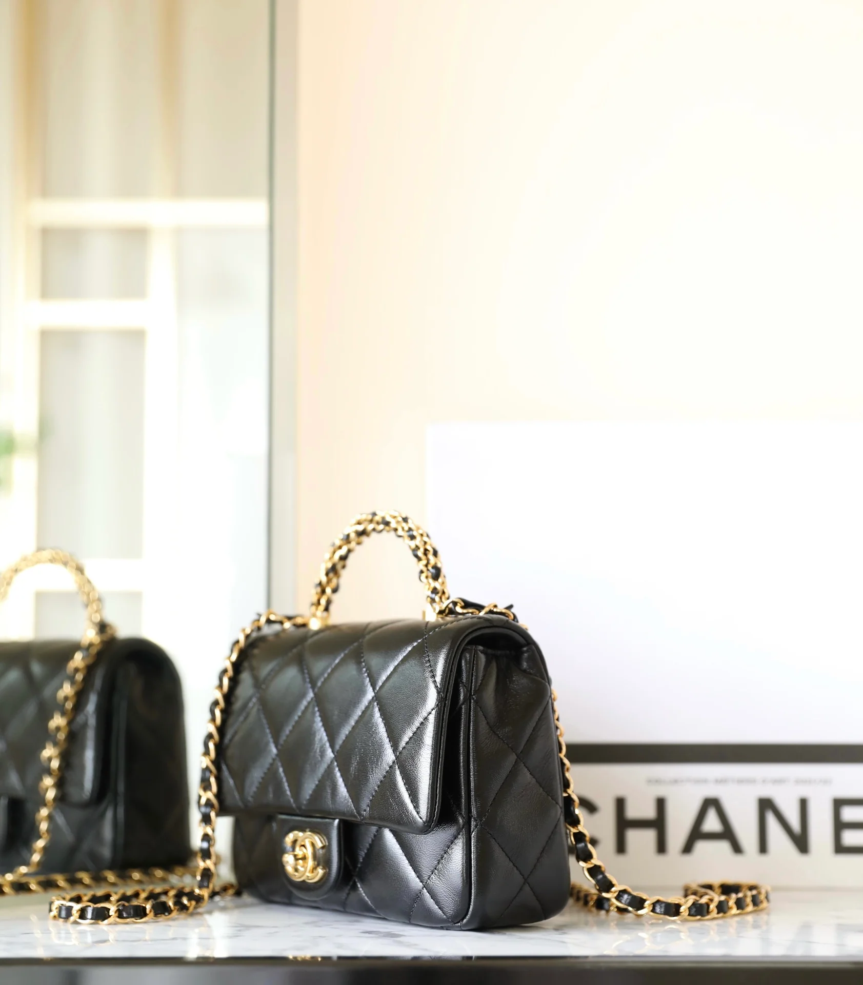 Маленькая черная сумка Chanel с клапаном и поворотной ручкой.