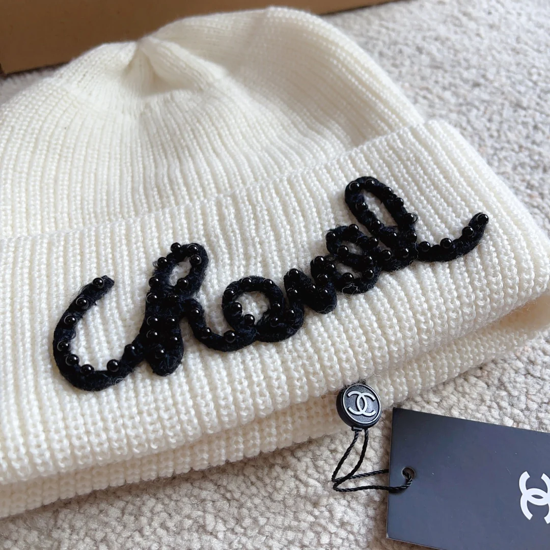 Плетеная шляпа Chanel с надписью курсивом — белая.