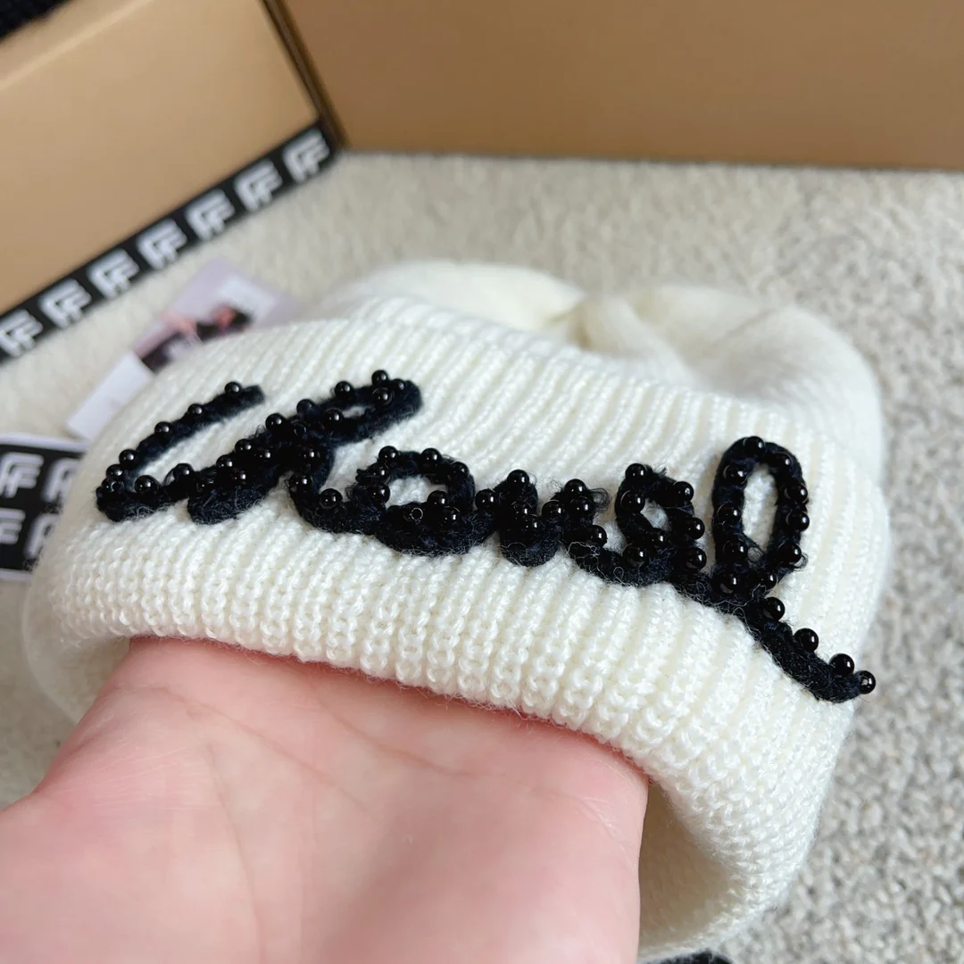 Плетеная шляпа Chanel с надписью курсивом — белая.