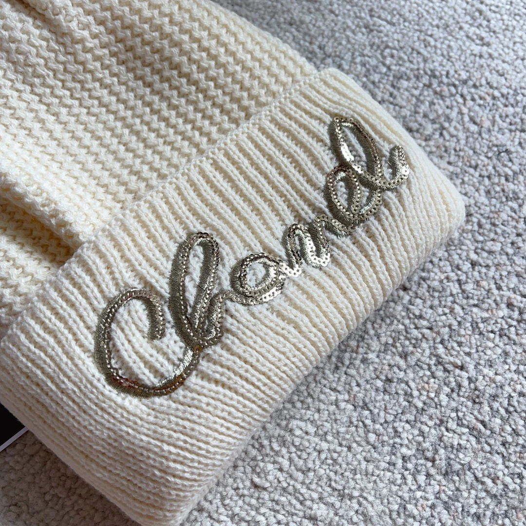Шапка Chanel с плетеным узором в виде курсивных букв, украшенная пайетками, белая.