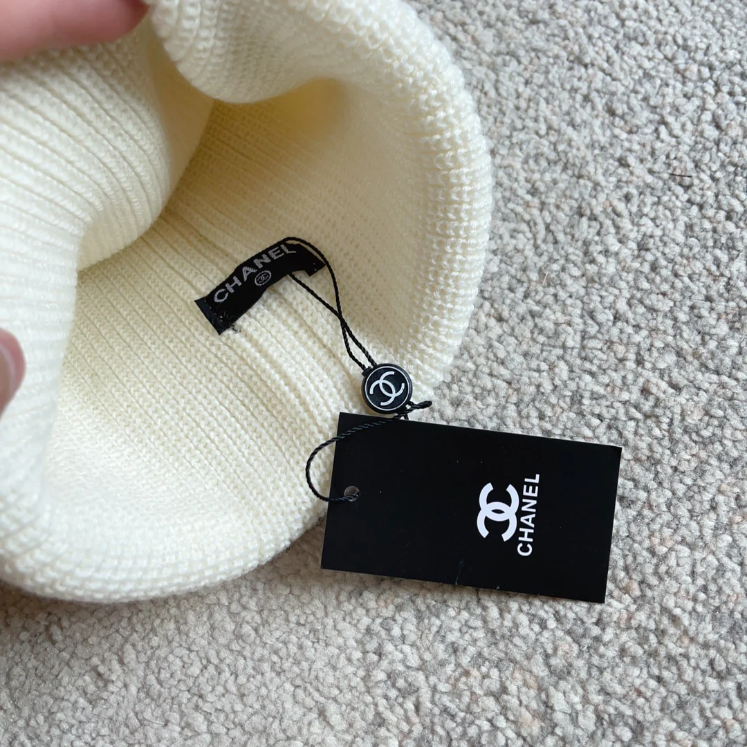 Плетеная шляпа Chanel с надписью курсивом — белая.