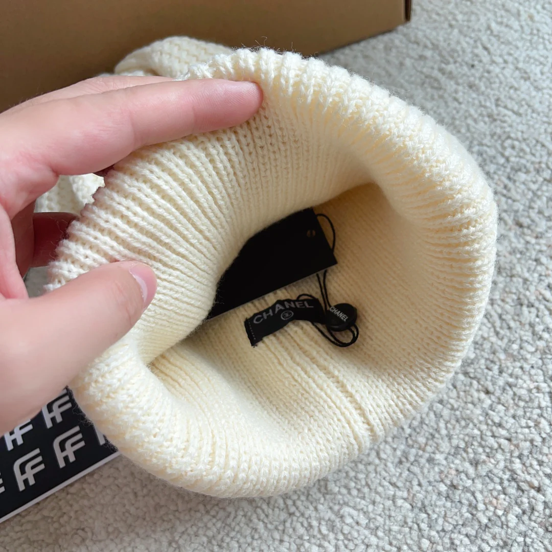 Шапка Chanel с плетеным узором в виде курсивных букв, украшенная пайетками, белая.