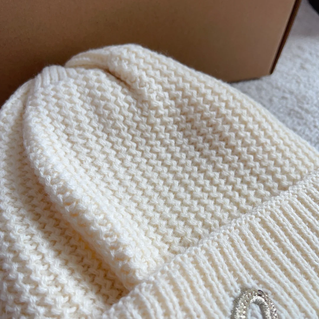 Шапка Chanel с плетеным узором в виде курсивных букв, украшенная пайетками, белая.